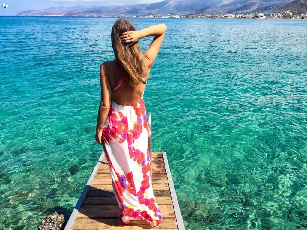 Sexy woman with long flower dress on the beach in Crete